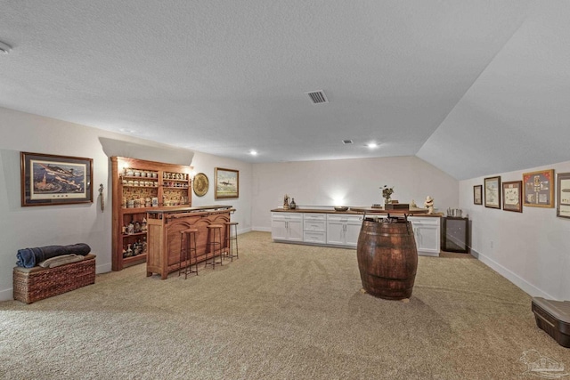 bar featuring visible vents, light carpet, a bar, and a textured ceiling