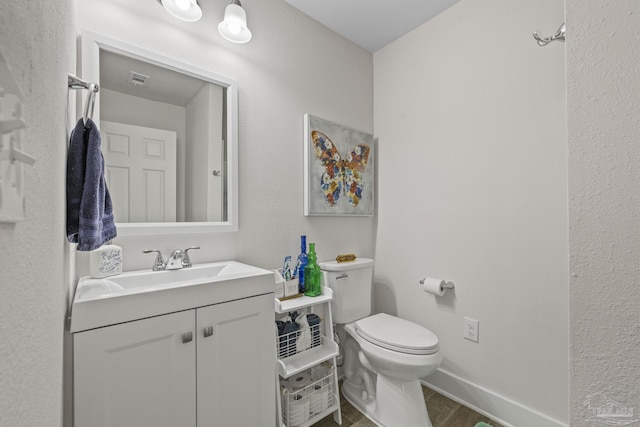 bathroom with vanity, toilet, and baseboards