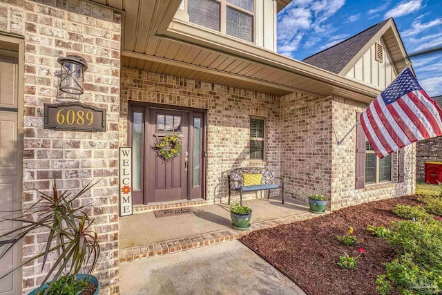 entrance to property featuring covered porch and brick siding