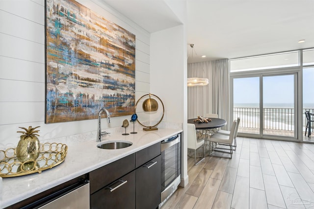 kitchen with pendant lighting, sink, beverage cooler, floor to ceiling windows, and a water view