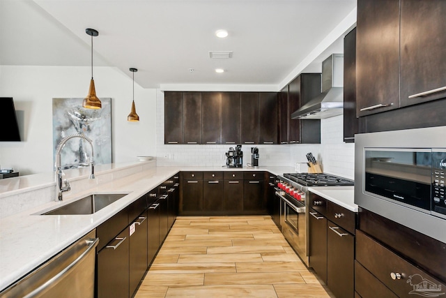 kitchen featuring sink, wall chimney range hood, hanging light fixtures, stainless steel appliances, and tasteful backsplash