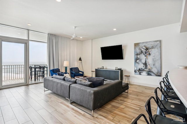 living room featuring a water view, a wall of windows, ceiling fan, and light hardwood / wood-style flooring