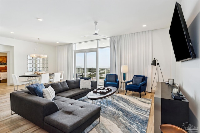 living room featuring ceiling fan, a wall of windows, and light hardwood / wood-style flooring