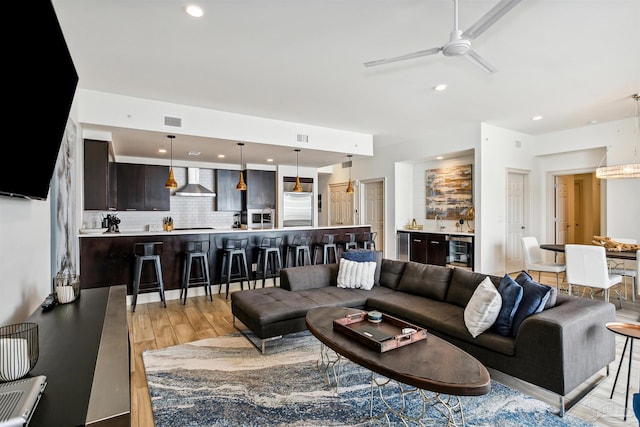 living room featuring ceiling fan, wine cooler, and light hardwood / wood-style floors