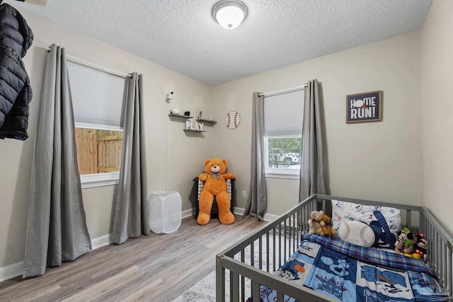 bedroom with hardwood / wood-style floors, a crib, and a textured ceiling