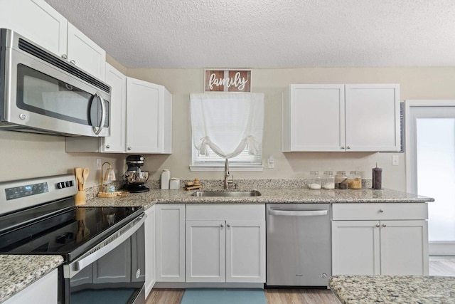 kitchen with white cabinetry, stainless steel appliances, sink, and a textured ceiling