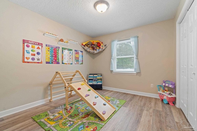 rec room with light hardwood / wood-style flooring and a textured ceiling