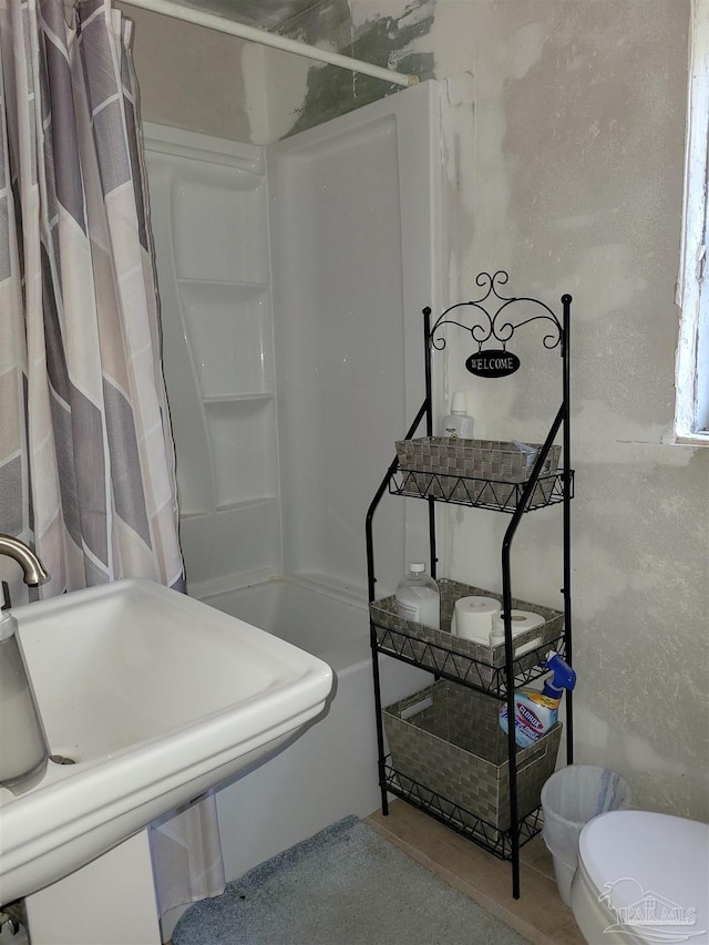 bathroom featuring a shower with shower curtain, toilet, and sink