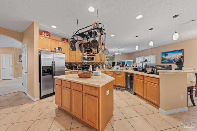 10108 Castleberry Blvd, Pensacola, FL 32526 - kitchen with stainless steel appliances, a peninsula, wine cooler, arched walkways, and light countertops