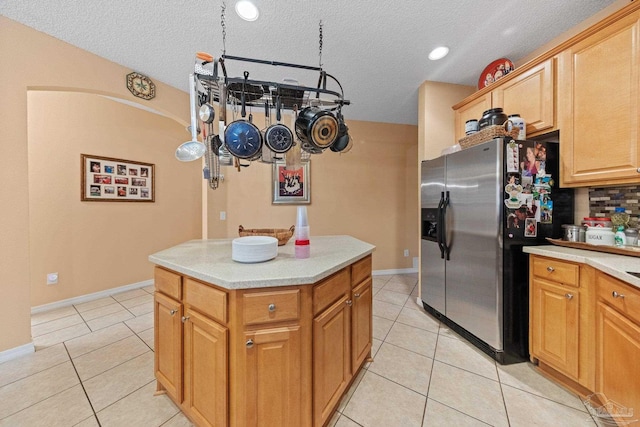 10108 Castleberry Blvd, Pensacola, FL 32526 - kitchen with stainless steel fridge, light tile patterned floors, light countertops, a center island, and a textured ceiling