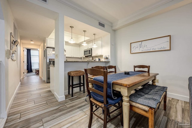 dining area with light hardwood / wood-style flooring and ornamental molding