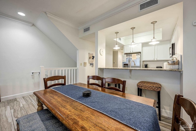 dining area featuring ornamental molding and light hardwood / wood-style flooring