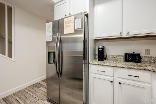 kitchen featuring white cabinets, light hardwood / wood-style floors, light stone countertops, and stainless steel fridge with ice dispenser