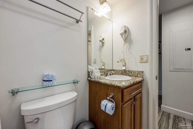 bathroom featuring hardwood / wood-style floors, vanity, toilet, and electric panel