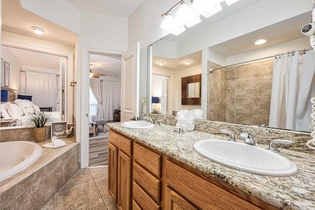 bathroom with tile patterned flooring, vanity, and tiled bath