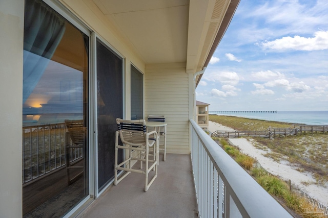 balcony featuring a view of the beach and a water view