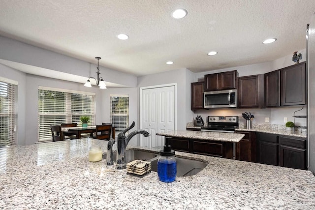 kitchen featuring sink, hanging light fixtures, light stone counters, stainless steel appliances, and a chandelier