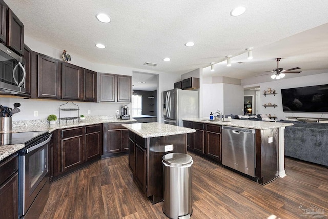 kitchen with a kitchen island, dark brown cabinetry, stainless steel appliances, and dark wood-type flooring