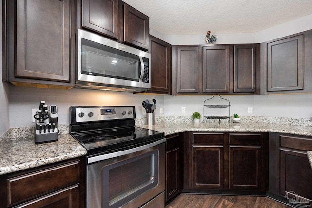 kitchen with dark brown cabinets, dark hardwood / wood-style flooring, stainless steel appliances, and a textured ceiling