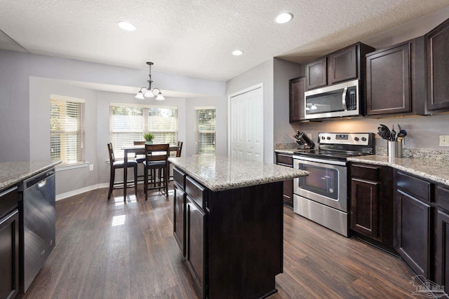 kitchen with a center island, dark wood-type flooring, appliances with stainless steel finishes, decorative light fixtures, and a chandelier