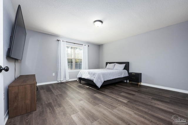 bedroom with dark hardwood / wood-style floors and a textured ceiling