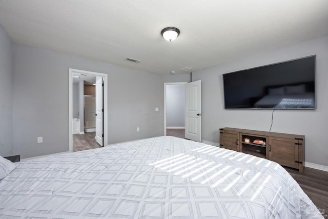 bedroom featuring ensuite bath and dark hardwood / wood-style flooring