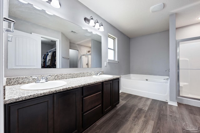 bathroom with wood-type flooring, vanity, and independent shower and bath