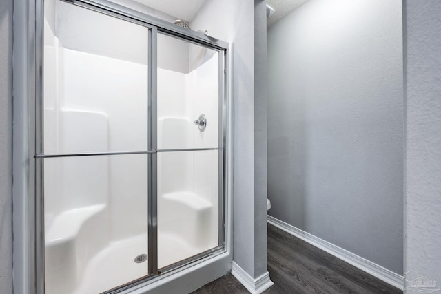 bathroom with wood-type flooring and a shower with door