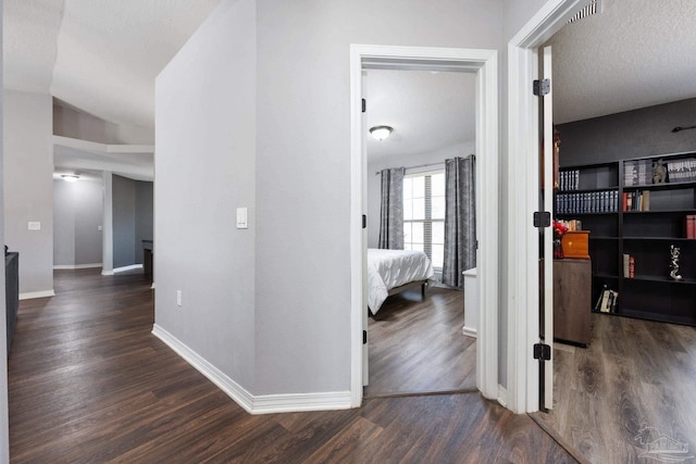 hall featuring a textured ceiling and dark hardwood / wood-style floors