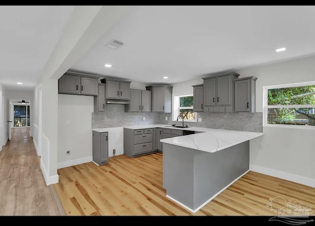 kitchen featuring backsplash, light hardwood / wood-style floors, gray cabinetry, and sink