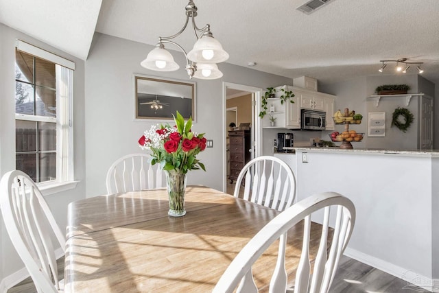 dining room with a textured ceiling, a chandelier, visible vents, baseboards, and dark wood finished floors