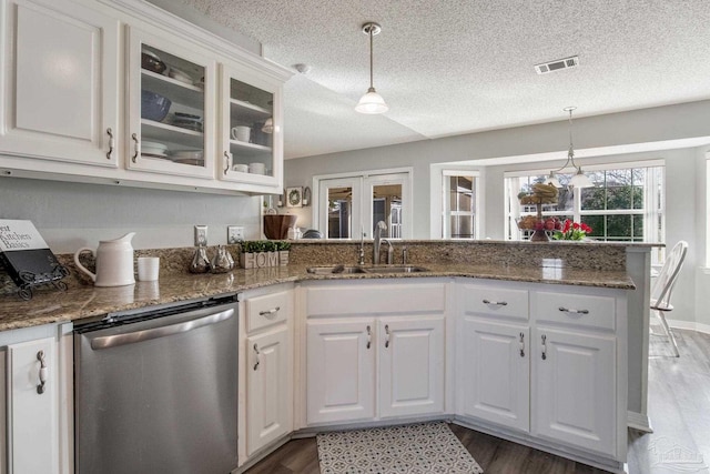 kitchen featuring visible vents, dishwasher, a peninsula, white cabinetry, and a sink