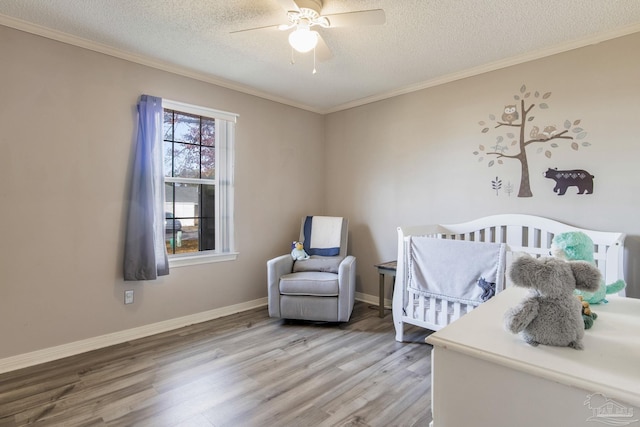 bedroom featuring baseboards, crown molding, light wood-style flooring, and a textured ceiling