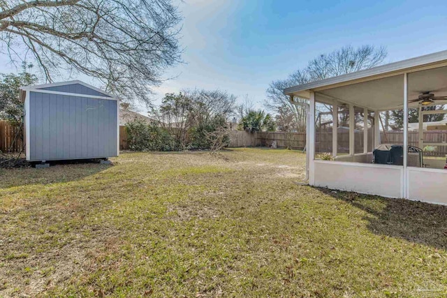 view of yard with an outbuilding, a fenced backyard, and a sunroom