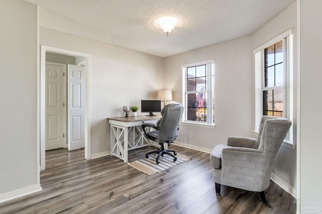 office area with a textured ceiling, baseboards, and wood finished floors