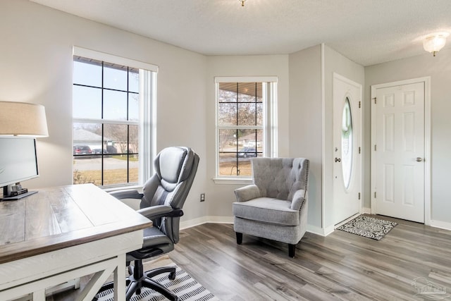 office area with a textured ceiling, baseboards, and wood finished floors