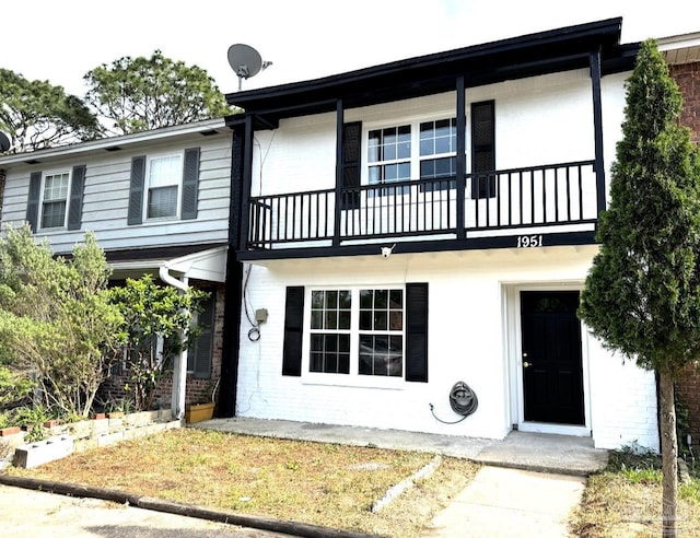 view of front facade with brick siding and a balcony