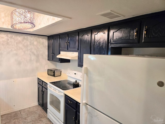 kitchen with white appliances, under cabinet range hood, visible vents, and dark cabinets