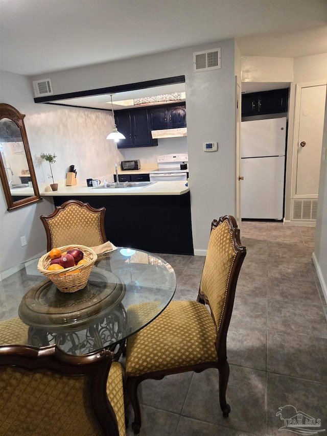 tiled dining room with visible vents, a sink, and baseboards