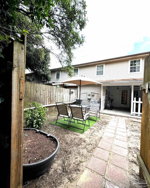 rear view of property with a patio, outdoor dining area, and fence