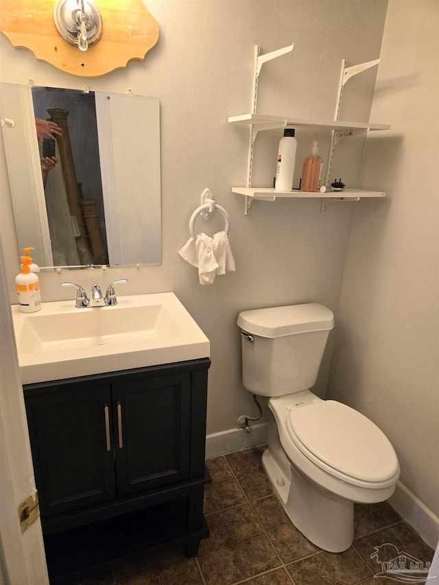 half bathroom with baseboards, tile patterned flooring, toilet, and vanity