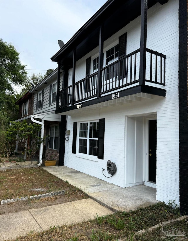 view of property exterior with brick siding and a balcony