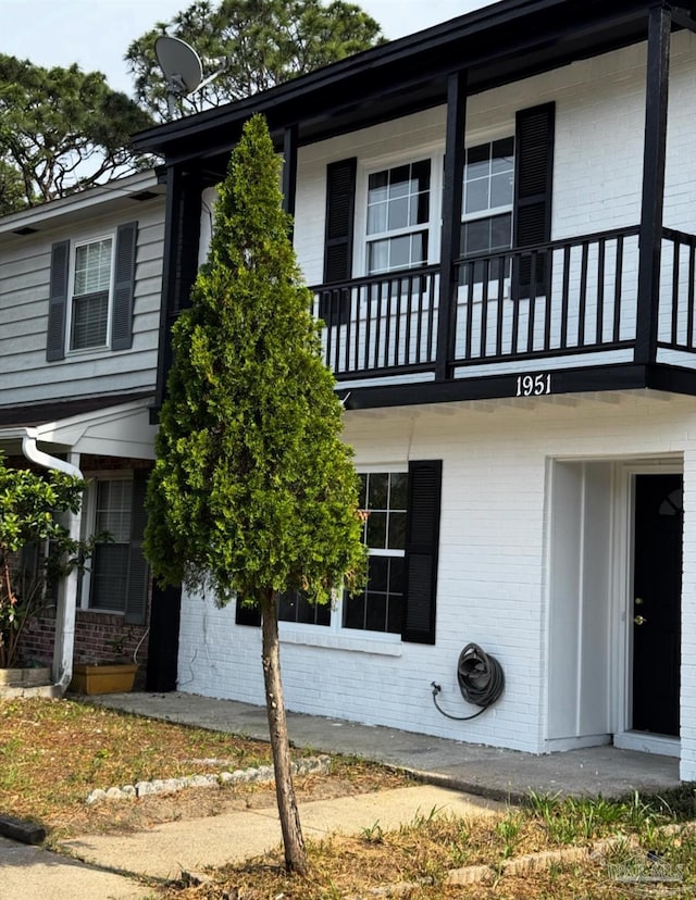 exterior space featuring brick siding and a balcony