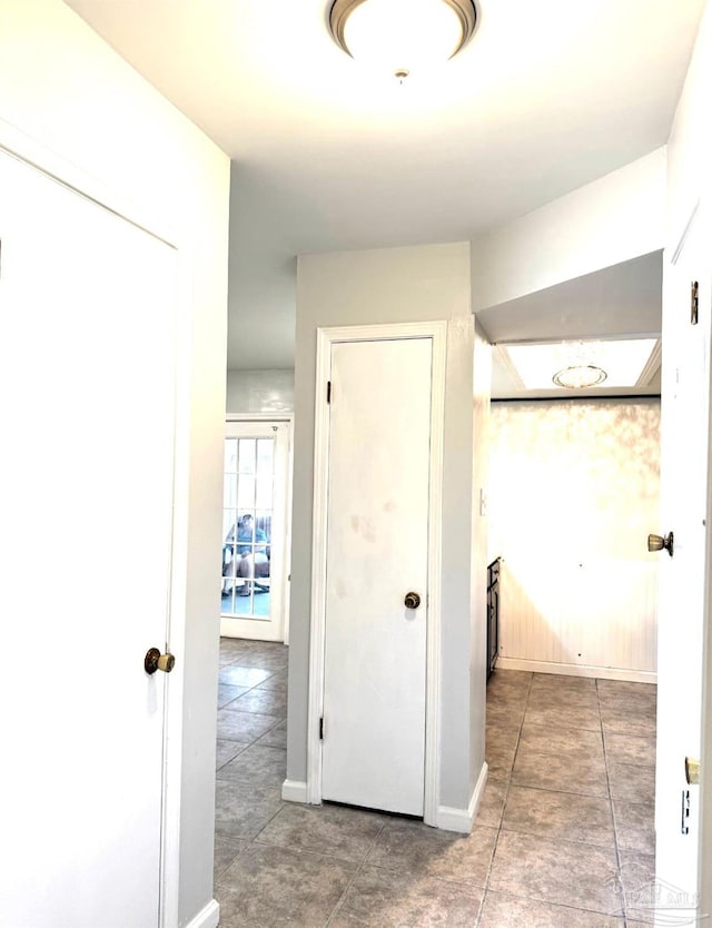 corridor featuring baseboards and tile patterned flooring