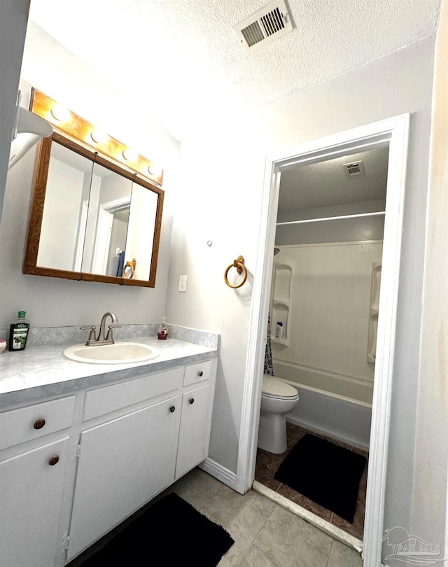 full bathroom with visible vents, vanity, toilet, a textured ceiling, and tile patterned floors