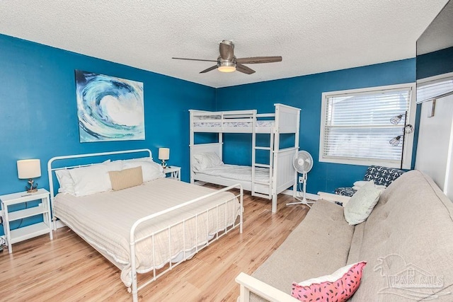 bedroom with ceiling fan, a textured ceiling, baseboards, and wood finished floors