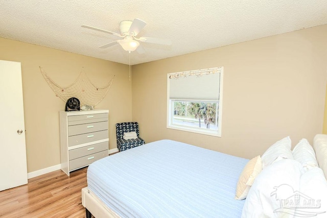 bedroom featuring a textured ceiling, light wood-type flooring, a ceiling fan, and baseboards