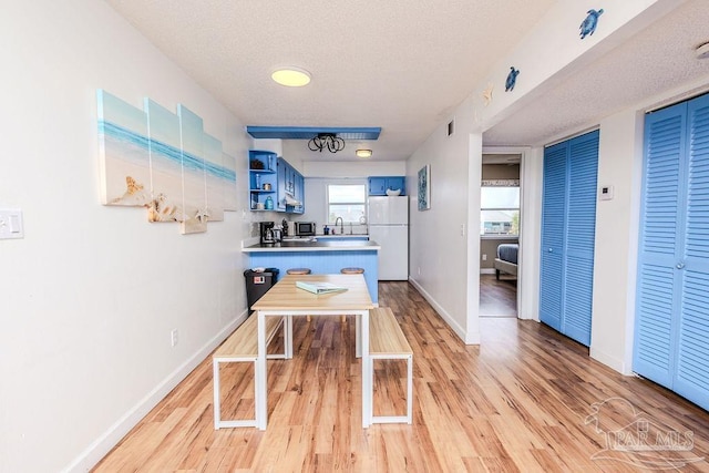 interior space featuring stainless steel microwave, freestanding refrigerator, a peninsula, a textured ceiling, and open shelves