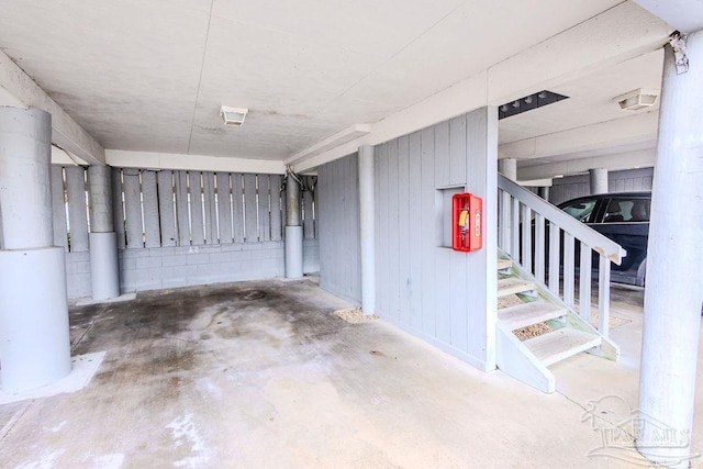 basement with concrete block wall, stairs, and a garage