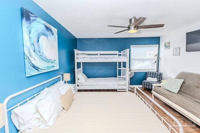 bedroom with a ceiling fan, a textured ceiling, and wood finished floors